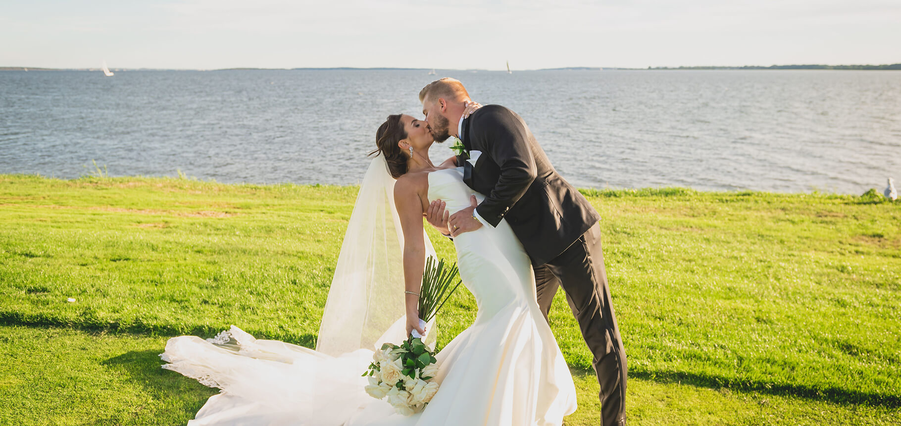 Groom kisses bride at seaside overlook